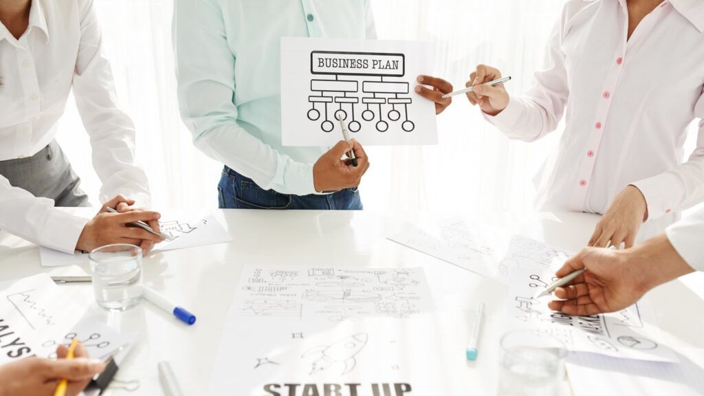 Hander som pekar pa en affarsplan med texten start up